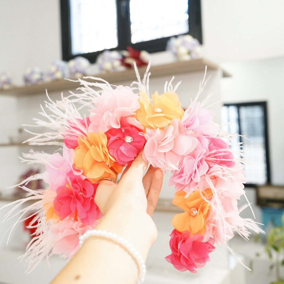 Bandeau floral en tissu avec détails roses, oranges et plumes
